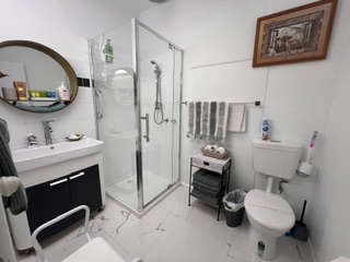 Bathroom with corner shower, vanity and round mirror