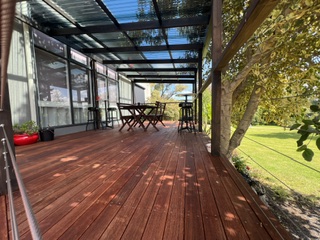 Covered rear deck with outdoor dining and bar setting overlooking the lawn
