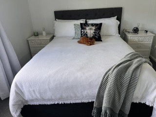 Queen bedroom with white bedlinen, bedside tables and throw rug