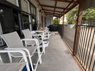 Fully fenced verandah with outdoor chairs and tables looking to the garden